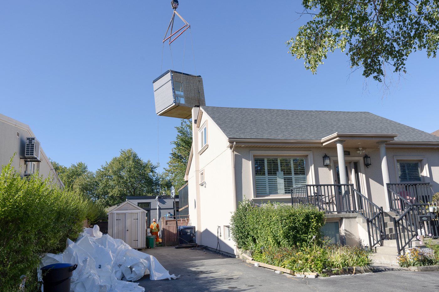 A module lifted over a bungalow on its way to the rear yard, Searle Avenue, North York